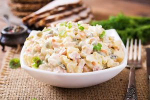 une table dressée avec une salade olivier dans une coupelle